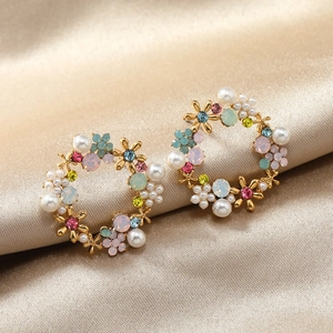 Elegant floral wreath earrings with colorful crystals and pearls on champagne silk fabric