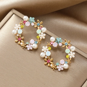 Detailed close-up of floral wreath earrings with colorful crystals and pearls on velvet
