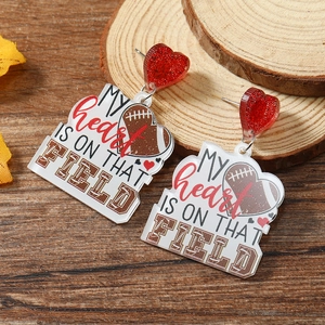 Detail of glitter red heart stud and acrylic rugby drop with My Heart text on wood
