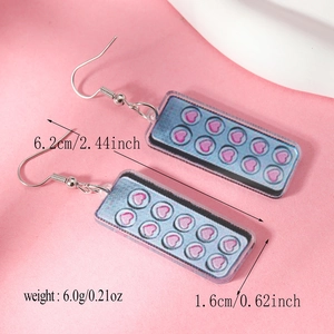 Detailed view of pink acrylic heart capsule earrings with size markings 6.2cm long