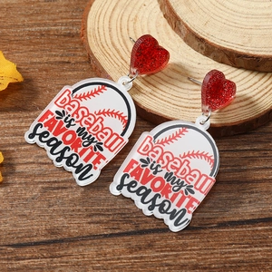 Macro shot of baseball-themed acrylic drop earrings with red glitter hearts on wood