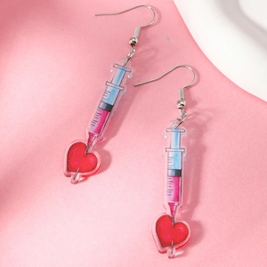 Detail of pink syringe earrings with red heart pendants made of acrylic material