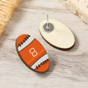 Detailed macro view of handmade wooden football earrings with vibrant orange color and metal studs