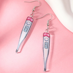 Detail of creative acrylic thermometer earring with heart motif on pink background