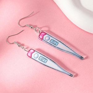 Close-up of pink thermometer shaped acrylic drop earrings on soft textured background