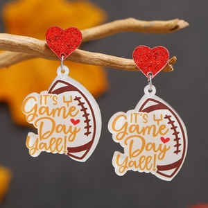 Macro shot of acrylic football earrings featuring red glitter hearts on rustic wood