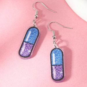 Macro detail of quirky pill-shaped acrylic earrings with blue and purple glitter fill