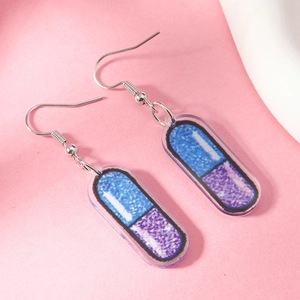 Detail of pink acrylic capsule earrings featuring blue and purple glitter filling