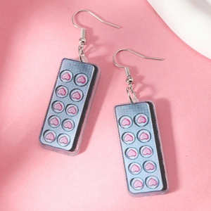 Detail of creative acrylic drop earrings featuring pink heart motifs on a blue base