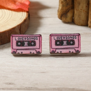 Pendientes de madera con diseño de casete retro rosa sobre una mesa de madera clara
