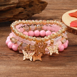 Detailansicht der rosa und goldfarbenen Perlenarmbänder mit Schmetterlingsanhängern