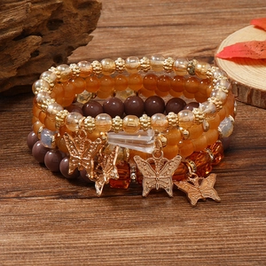 Detailansicht der mehrlagigen Boho-Perlenarmbänder mit goldenen Schmetterlingsanhängern