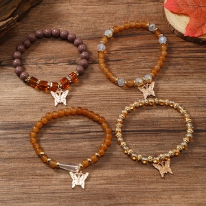 Detailsicht von vier Boho-Perlenarmbändern mit Schmetterlingsanhängern auf Holz