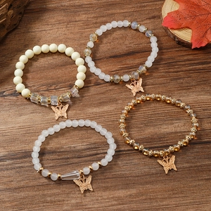 Details des 4-teiligen Perlenarmband-Sets mit goldenem Schmetterling auf Holzgrund