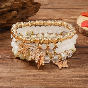 Detailaufnahme des mehrlagigen Perlenarmband-Sets mit goldenen Schmetterlingsanhängern