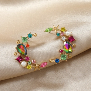 Elegant crescent gold earrings with colorful gemstones and pearls on silk fabric background