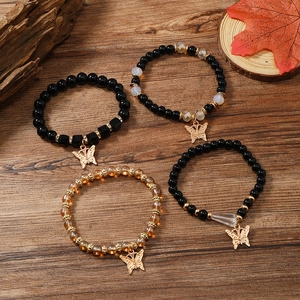 Detailaufnahme von vierlagigen Boho-Armbändern mit goldenen Schmetterlingen auf Holz
