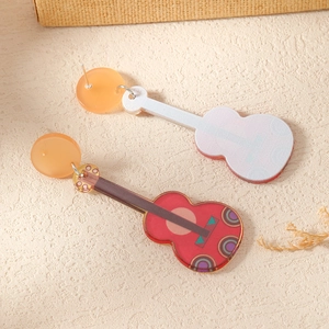 Detail view of red guitar earrings with geometric patterns and orange round charms