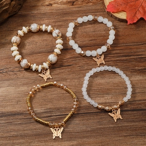 Details des 4-teiligen Armband-Sets mit weißen Perlen und goldenen Schmetterlingsanhängern