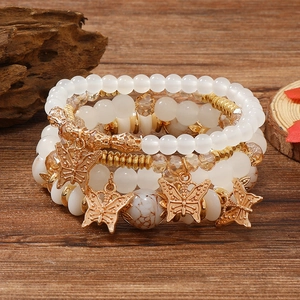 Detail eines mehrlagigen Boho-Perlenarmband-Sets mit goldenen Schmetterlingsanhängern