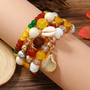 Nahaufnahme des mehrlagigen Boho-Perlenarmband-Sets mit Muscheln auf einem rosa Handmodell