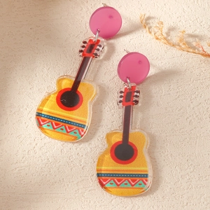 Macro detail of acrylic guitar earring with pink studs and yellow folk pattern finish