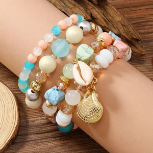 Detail von mehrlagigen Boho-Perlenarmbändern mit Muschelanhänger und bunten Perlen