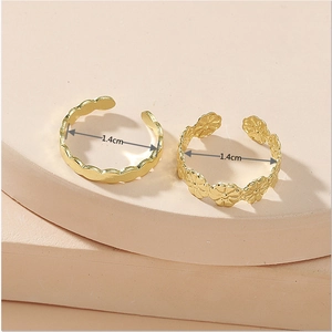 Detailed view of two gold open rings featuring wave and daisy floral patterns with 1.4cm inner diameter