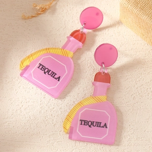 Macro detail of creative pink acrylic tequila bottle earrings with engraved black text