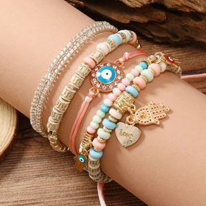 Detail von mehrlagigen Boho-Armbändern mit bösem Blick, Hamsa-Hand und Herzanhängern