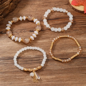 Detailaufnahme von mehrlagigen Boho-Armbändern mit Harzperlen und goldenen Quastenanhängern