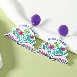 Détail de boucles d'oreilles livre en acrylique avec fleurs et texte de lecture