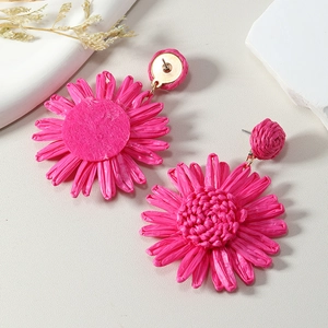 Detail of pink raffia sunflower earrings with handcrafted woven texture for beach vacation
