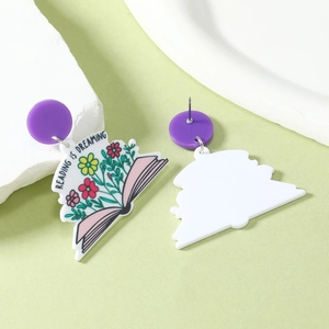 Détail de boucles d'oreilles asymétriques en acrylique avec motif livre et fleurs colorées
