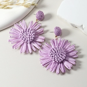 Detailed close-up of lavender purple raffia sunflower earrings on textured background