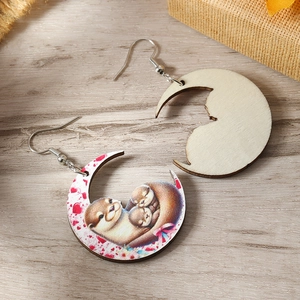 Close-up of wooden crescent earrings with cute otters and heart pattern details