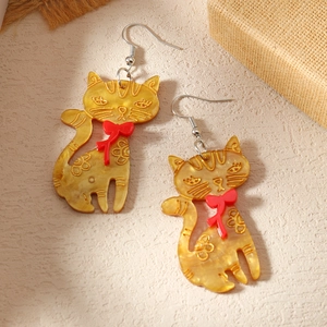Detailansicht der gelben Acryl-Ohrringe im Katzendesign mit Blumen und roten Schleifen
