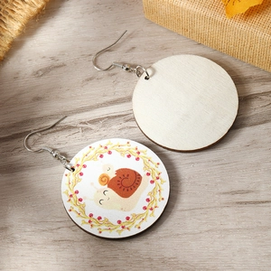 Close-up of wooden earrings with cartoon snail and floral design on rustic wooden table