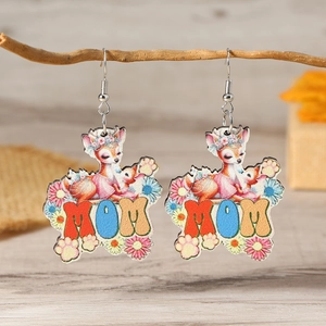 Macro detail of wooden earrings with cartoon deer floral print and MOM text hanging on a branch