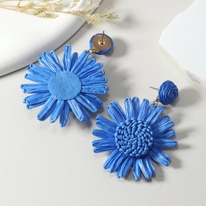 Detailed macro view of handmade blue raffia sunflower earrings with woven texture