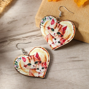 Detailed view of heart-shaped wooden earrings with cute cat and floral illustration