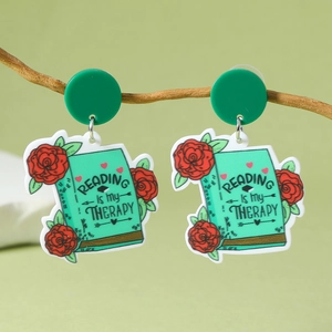 Détail de boucles d'oreilles livre en acrylique avec roses et texte de lecture