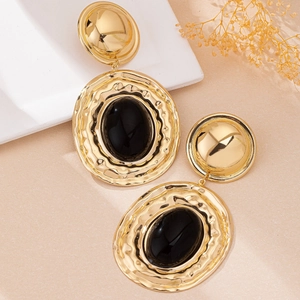 Detail of vintage bohemian drop earrings with hammered gold texture and black oval stone