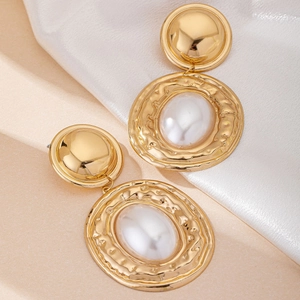 Detailed close-up of retro gold geometric earrings with pearls on silk background