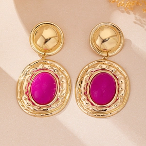 Close-up of vintage gold hammered metal earrings with magenta oval stone inlays