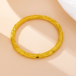 Macro-opname van een gouden armband met reliëfschubben en een ingezette groene zirkoon