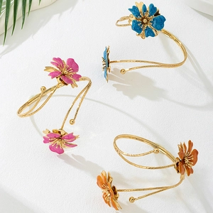 Detail of colorful enamel flower arm cuffs in blue pink and orange with gold finish