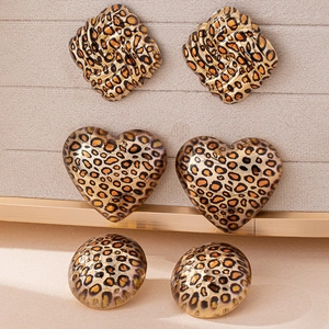 Three pairs of leopard print earrings including heart and geometric shapes on a jewelry board
