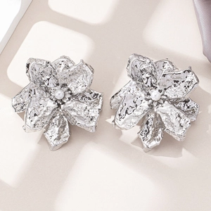 Detail of silver oversized floral earrings with hammered metal texture and pearl center
