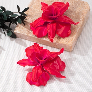 Auffällige magentafarbene XXL Blumenohrringe mit Glanzfinish auf dekorativem Steingrund